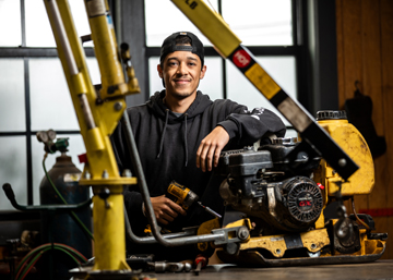 man standing by heavy equipment and smiling
