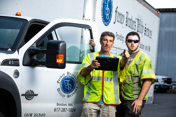 two feeney workers standing by a feeney truck and looking at an ipad