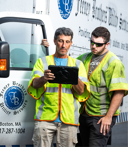 two feeney workers standing by a feeney truck and looking at an ipad